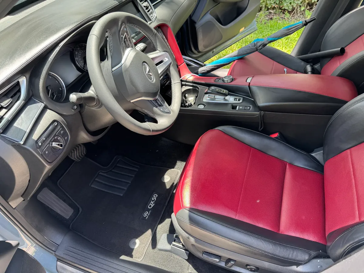 Infiniti QX50 interior after detailing — clean red and black leather seats and mats