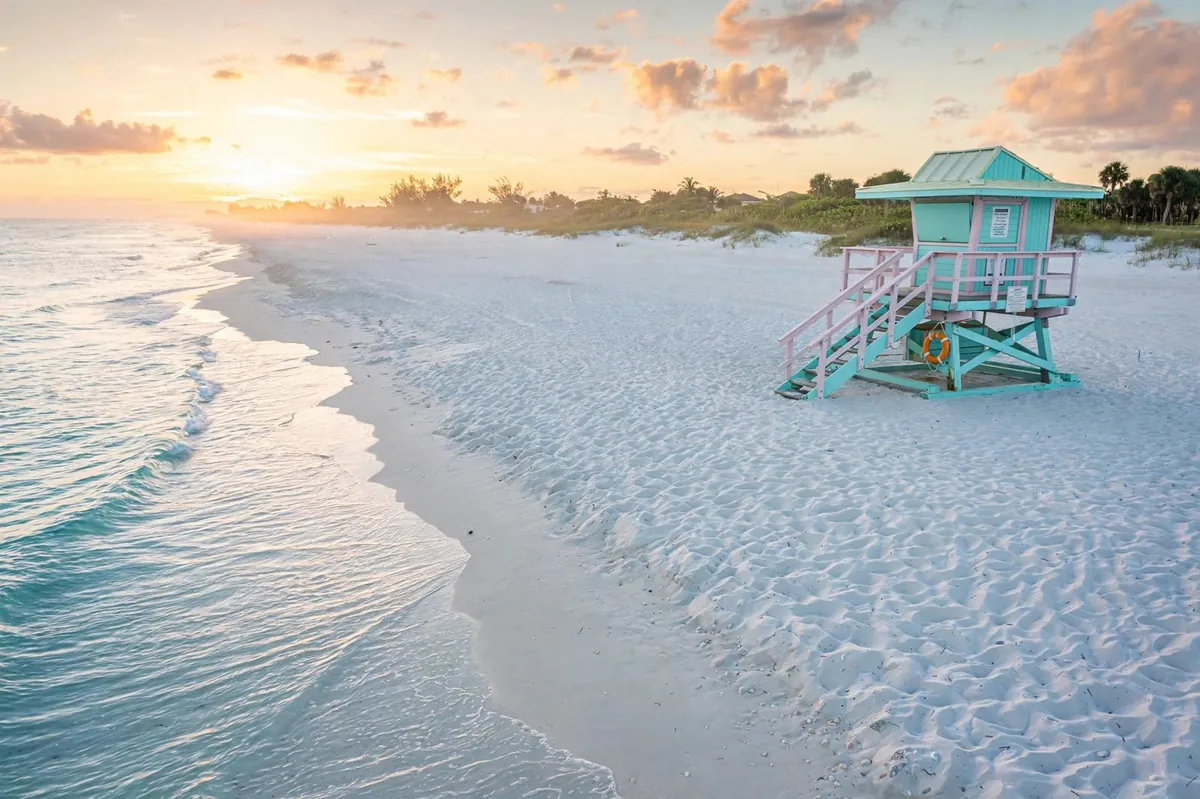 Siesta Beach at sunrise — powdery white quartz sand, turquoise Gulf water, and a lifeguard stand